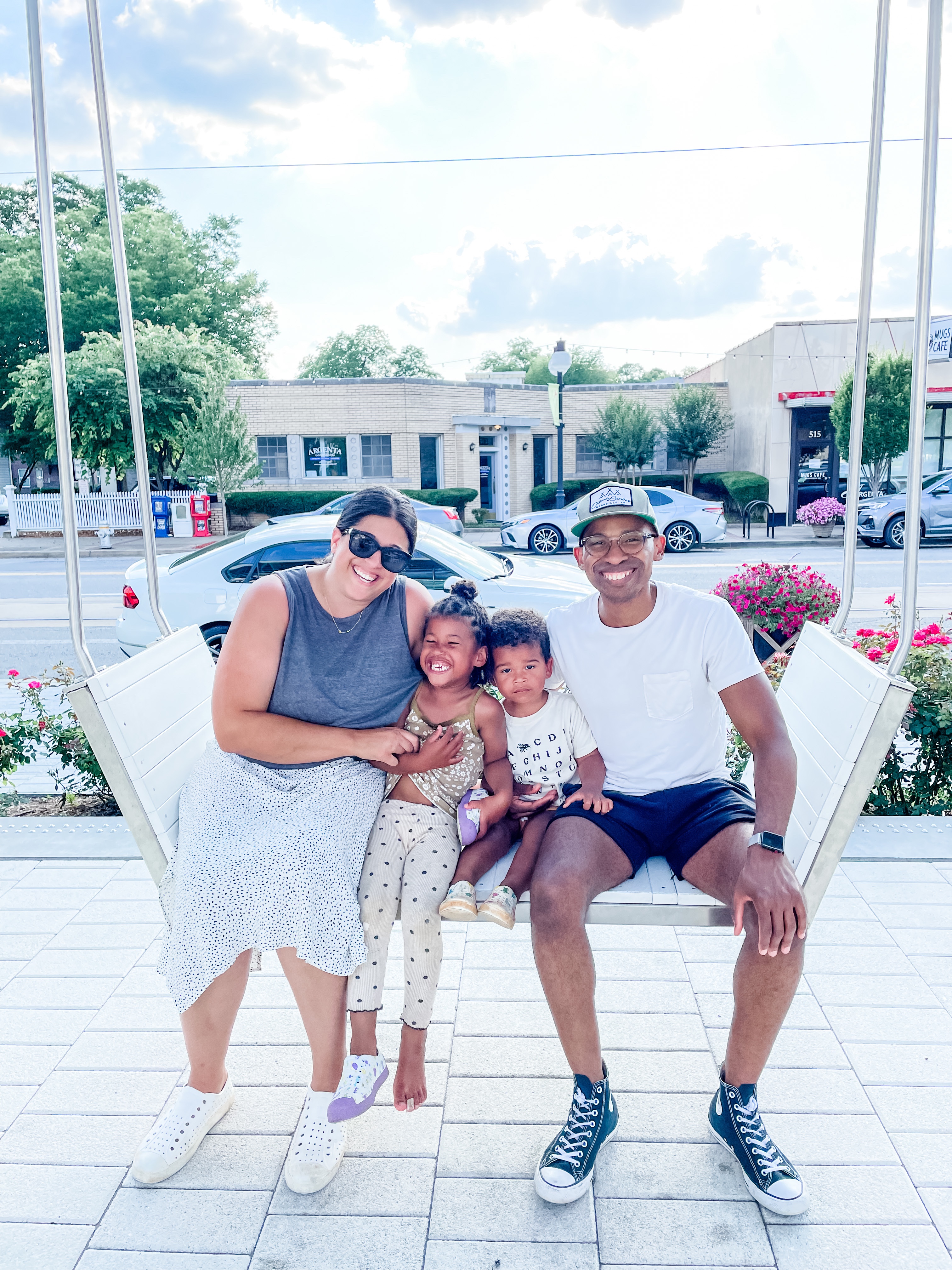 family of four sitting on swinging bench smiling at the camera