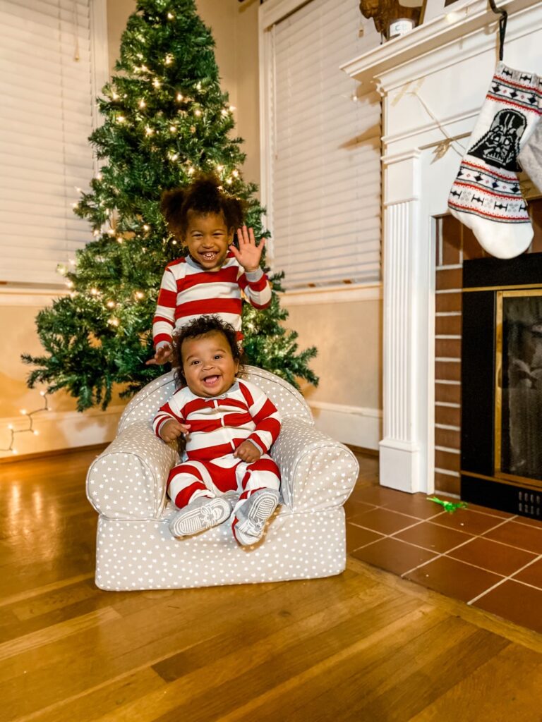 siblings in front of Christmas tree in matching pajamas