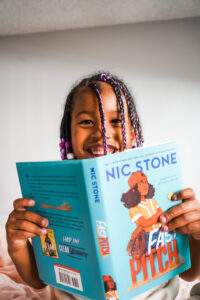 little girl reading book and smiling